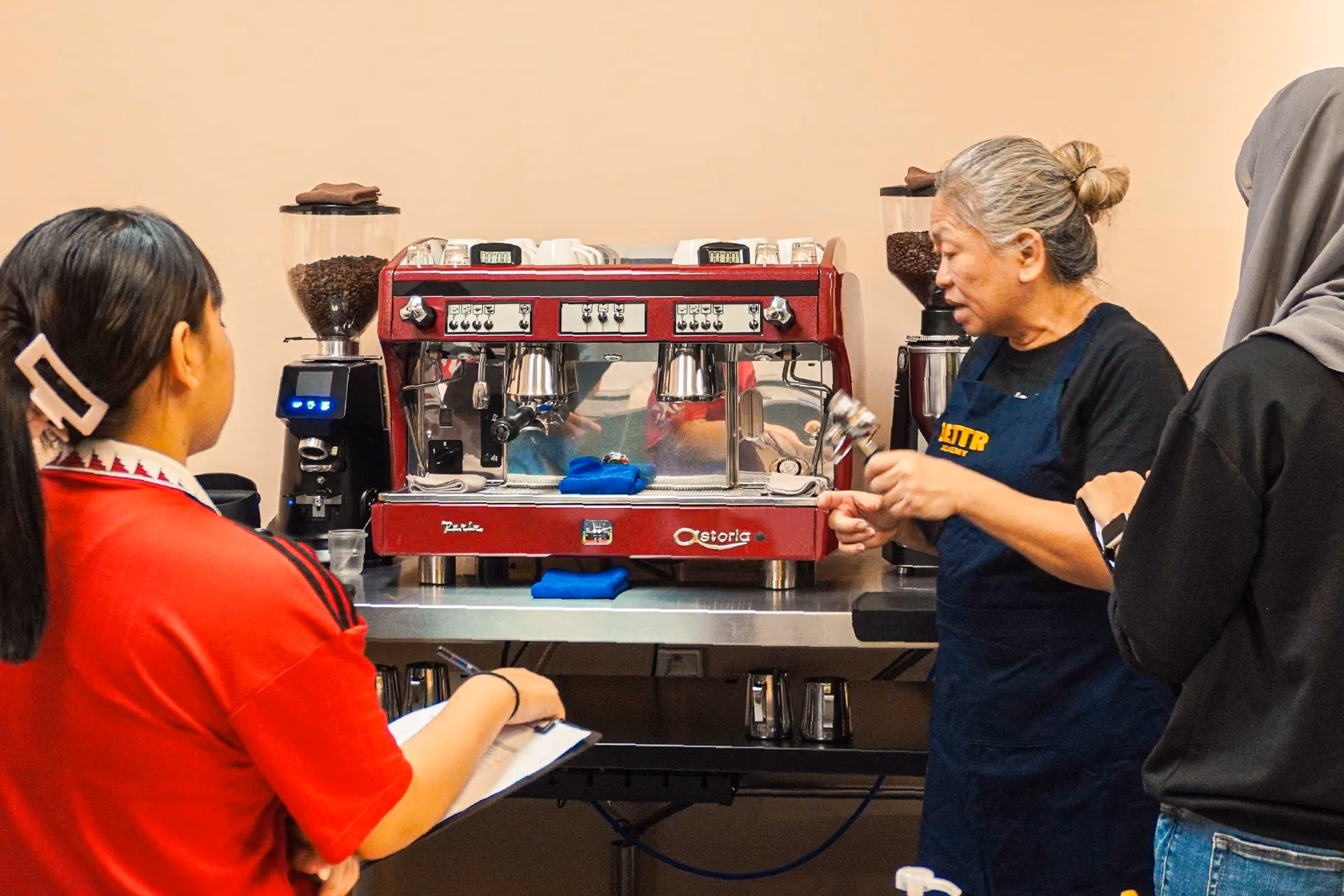 Trainer instructing youths on how to operate an espresso machine.