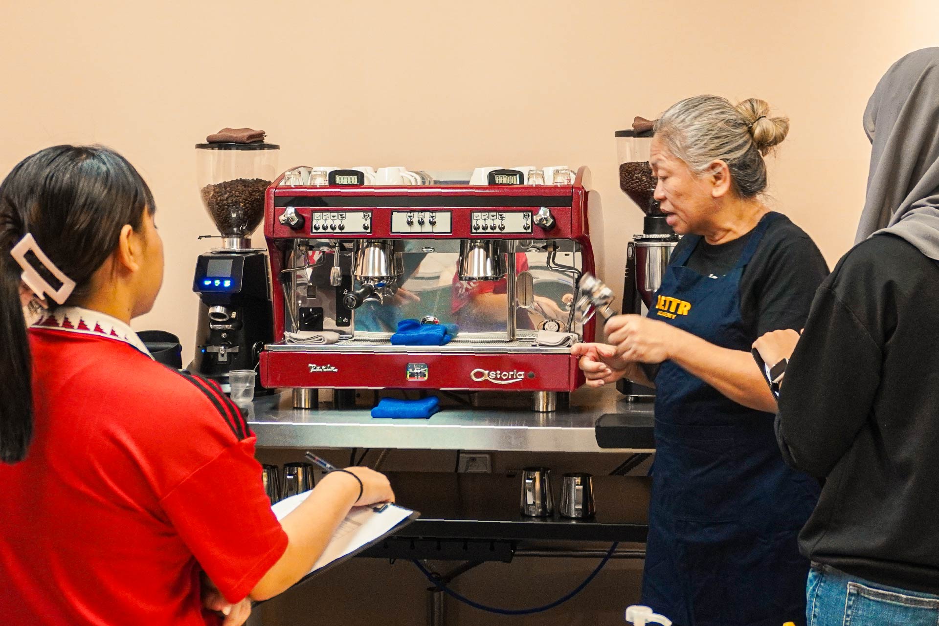 Trainer instructing youths on how to operate an espresso machine.