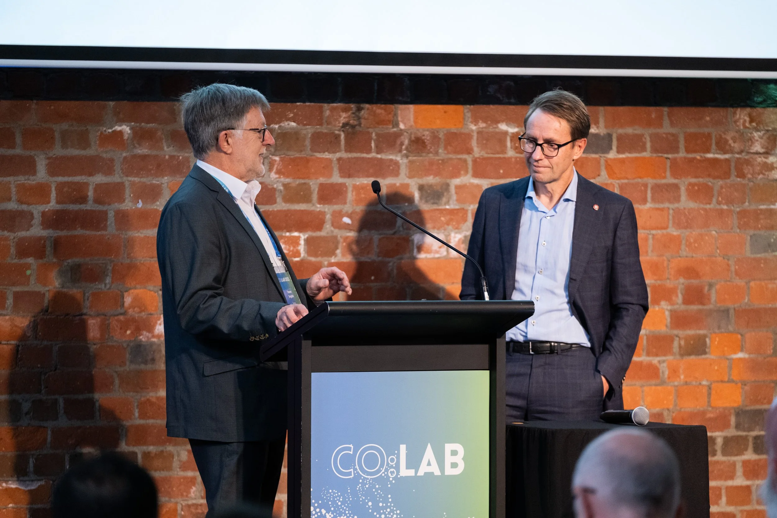 Two speakers on stage at the Co:Lab event