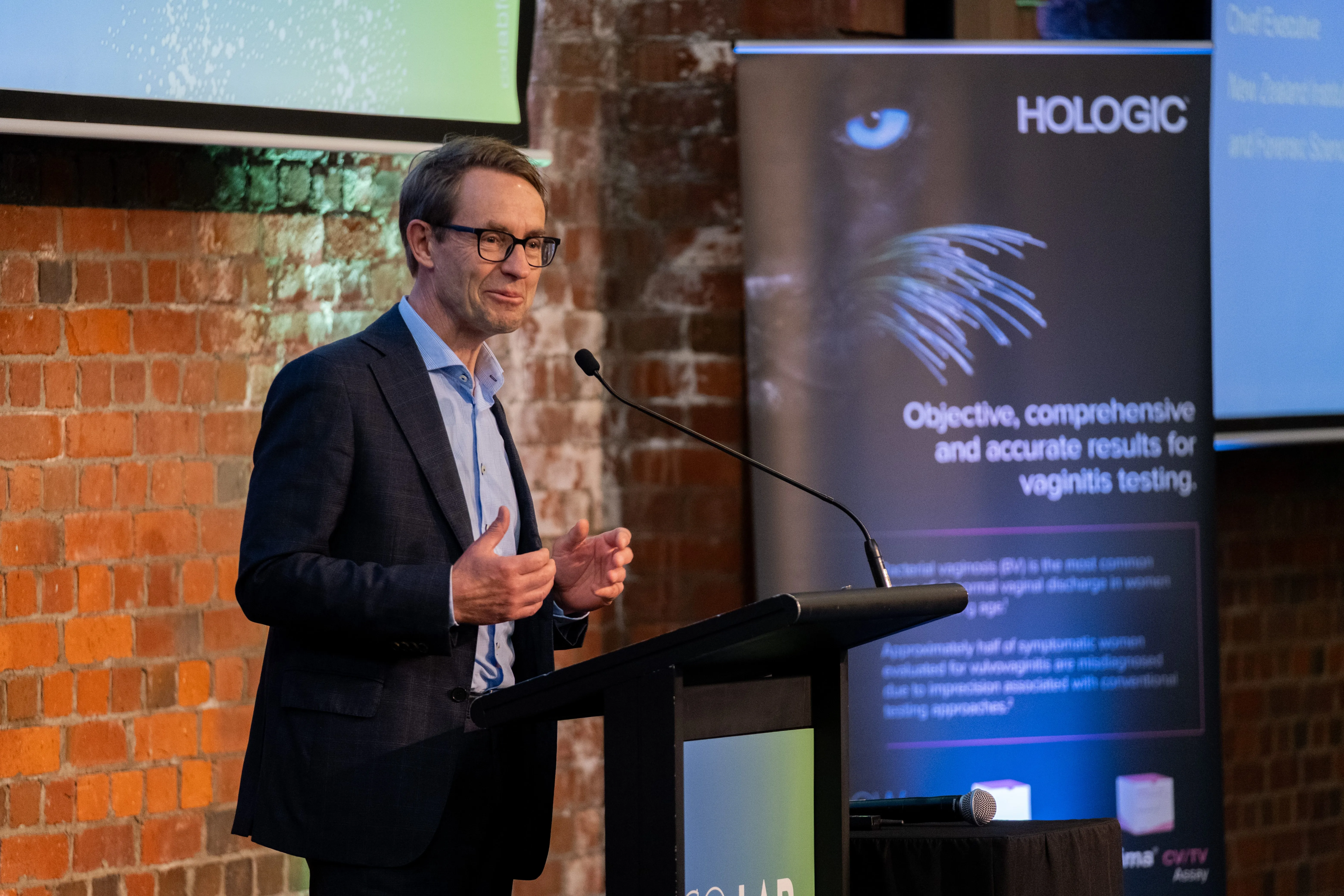 Speaker at a podium with a Hologic banner behind him