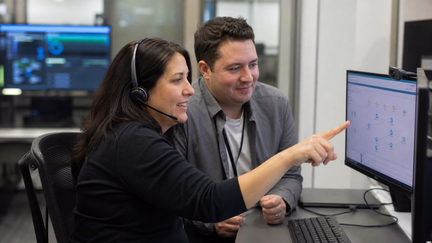 Help desk agent consults colleague on network diagram monitors