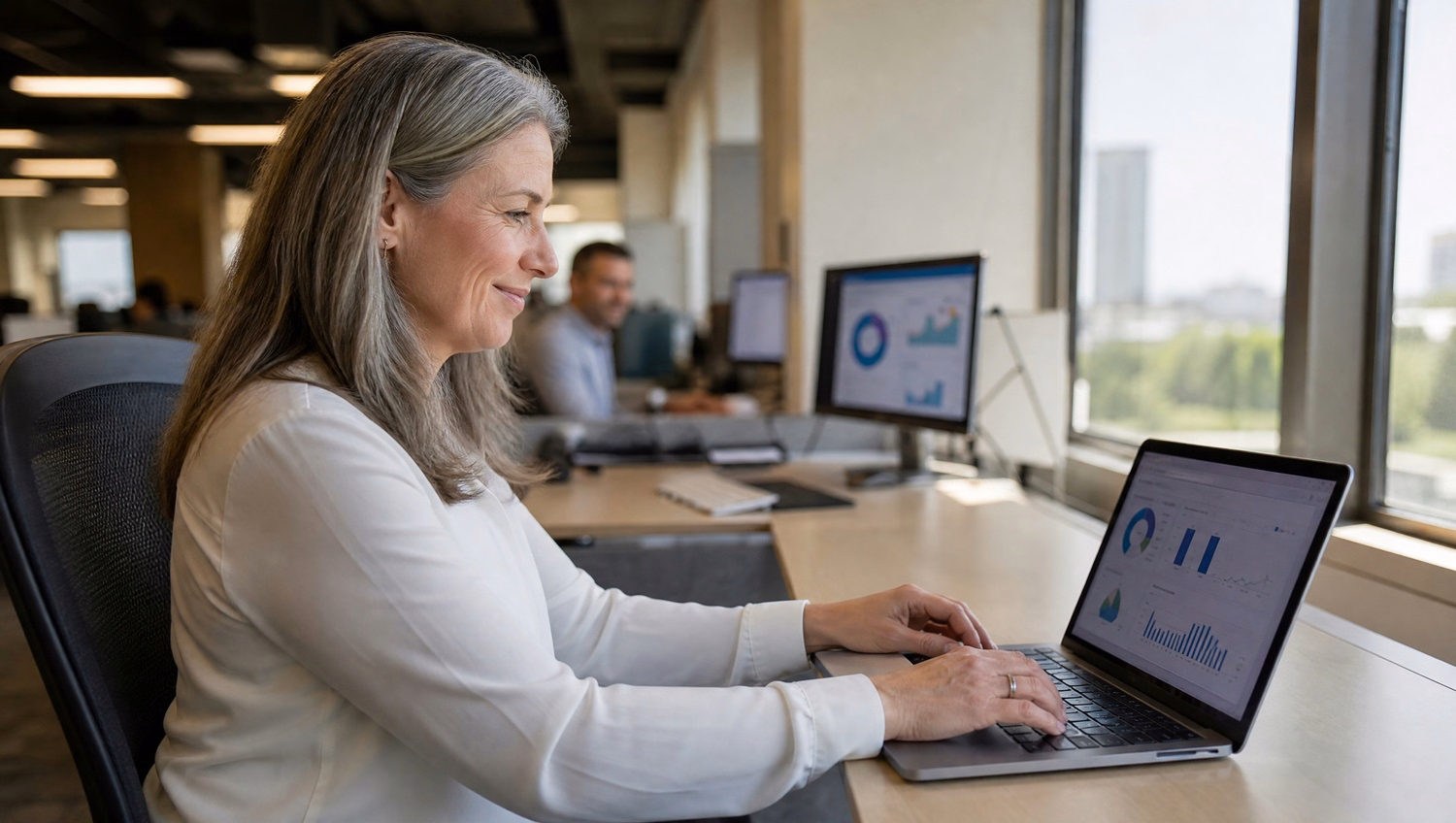 Woman at laptop reviews charts by window daylight 63 chars