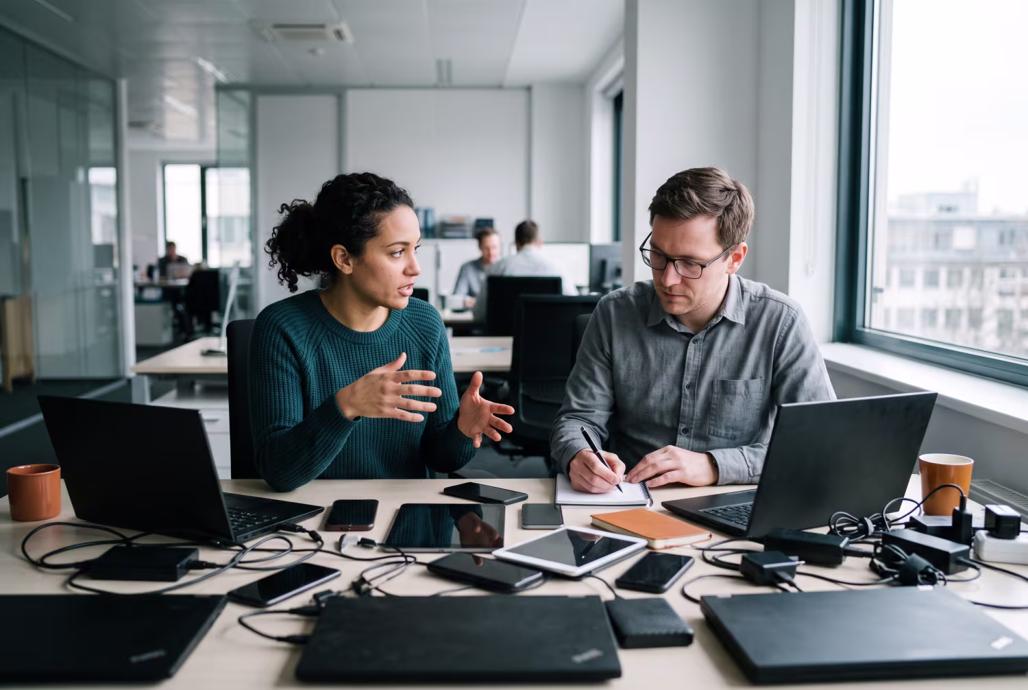 Two professionals discussing endpoint security near cluttered desk