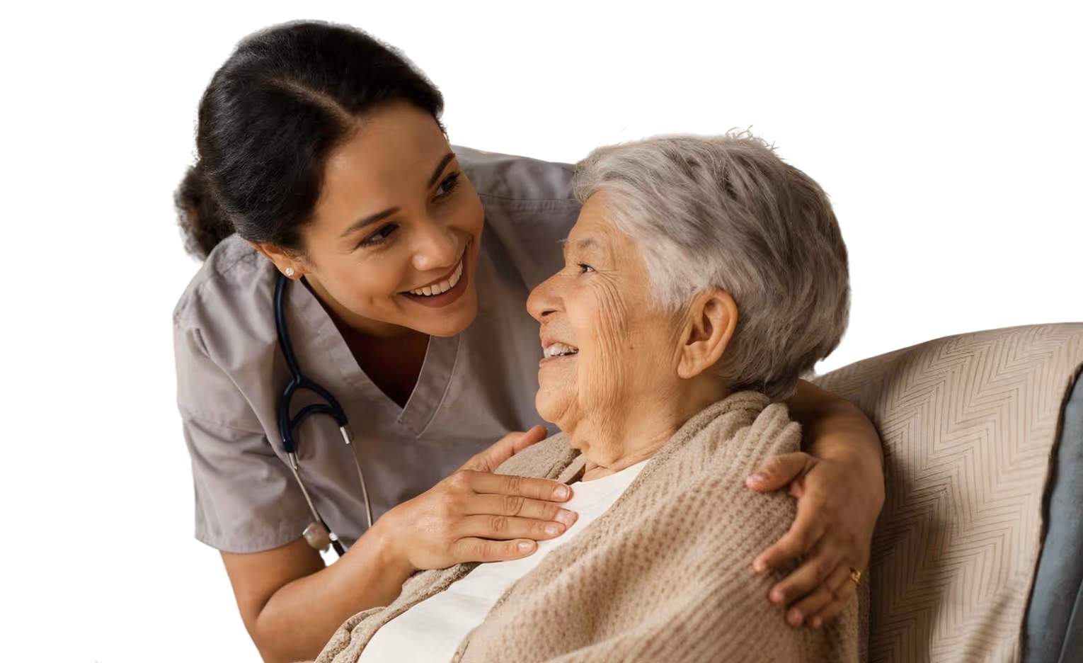 Caregiver with stethoscope smiling warmly at an elderly woman wrapped in a beige blanket.