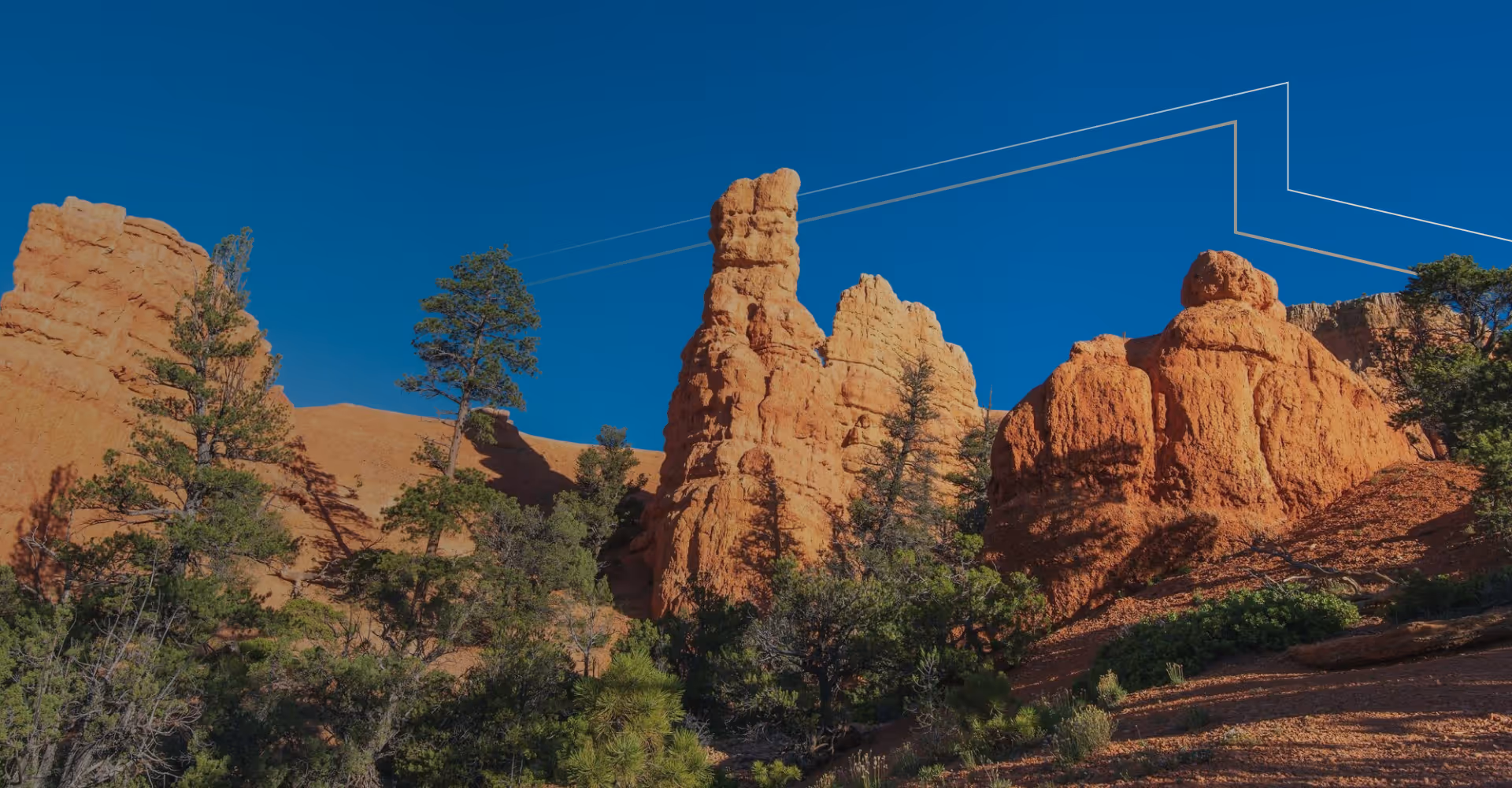 Red rock formations and green trees under a clear blue sky in a desert landscape.