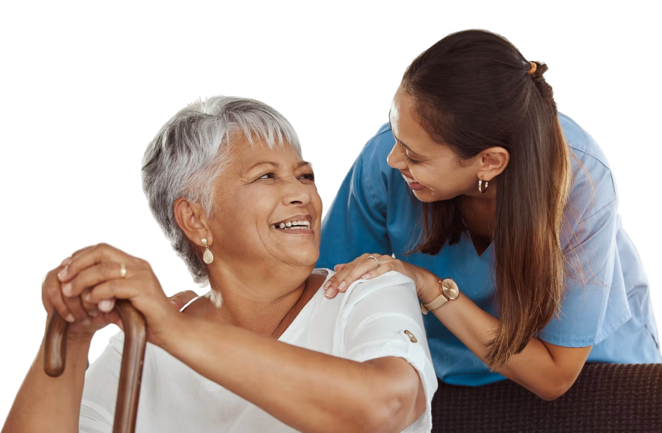 Young caregiver in blue scrubs smiling and supporting an elderly woman with a cane.