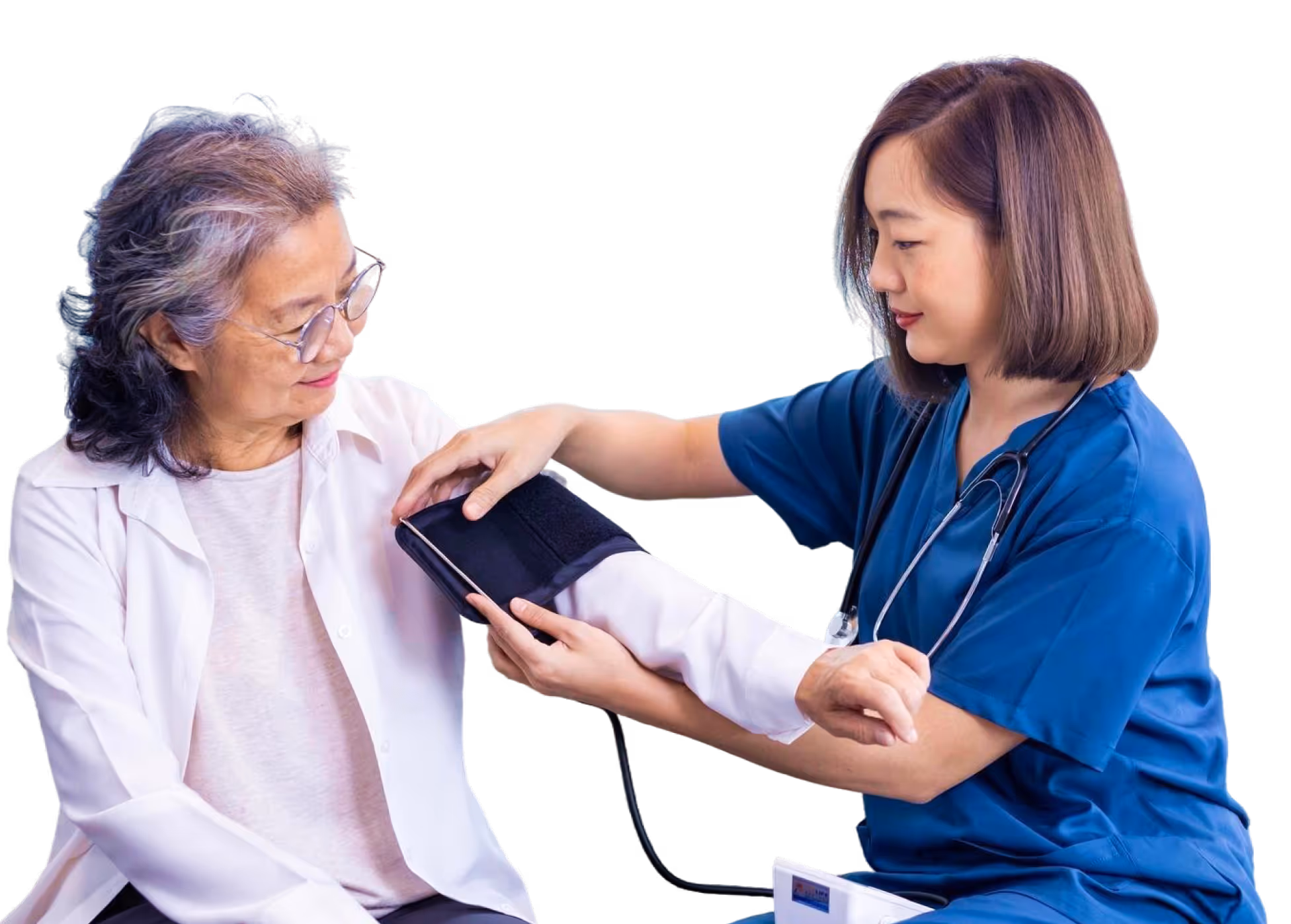 Nurse in blue scrubs checking blood pressure of elderly woman with glasses and gray hair.