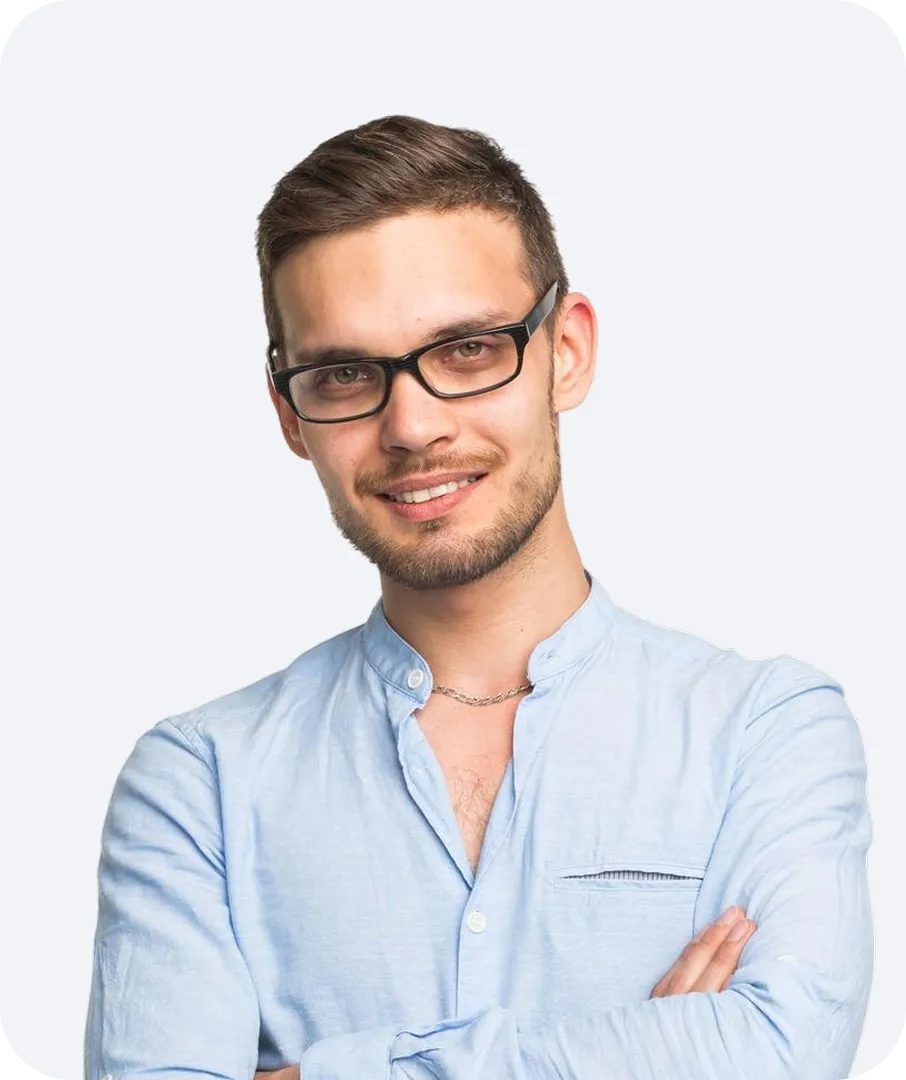 Smiling man with glasses wearing a light blue shirt and a silver chain necklace, arms crossed.