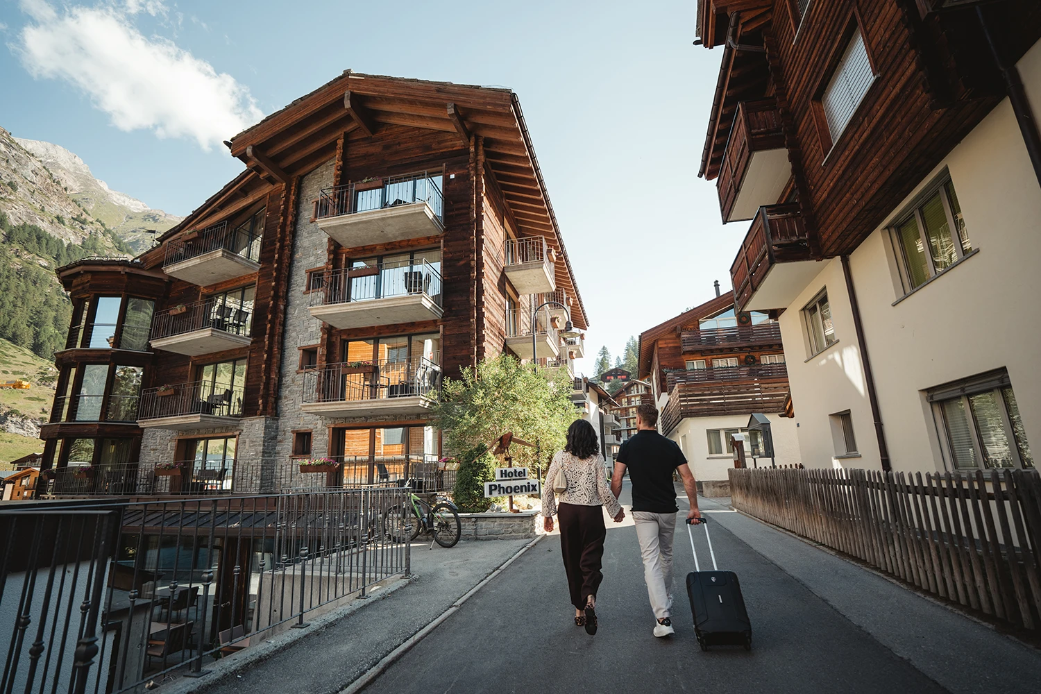 Paar mit Koffer auf dem Weg durch eine Gasse im Wiesti-Quartier in Zermatt