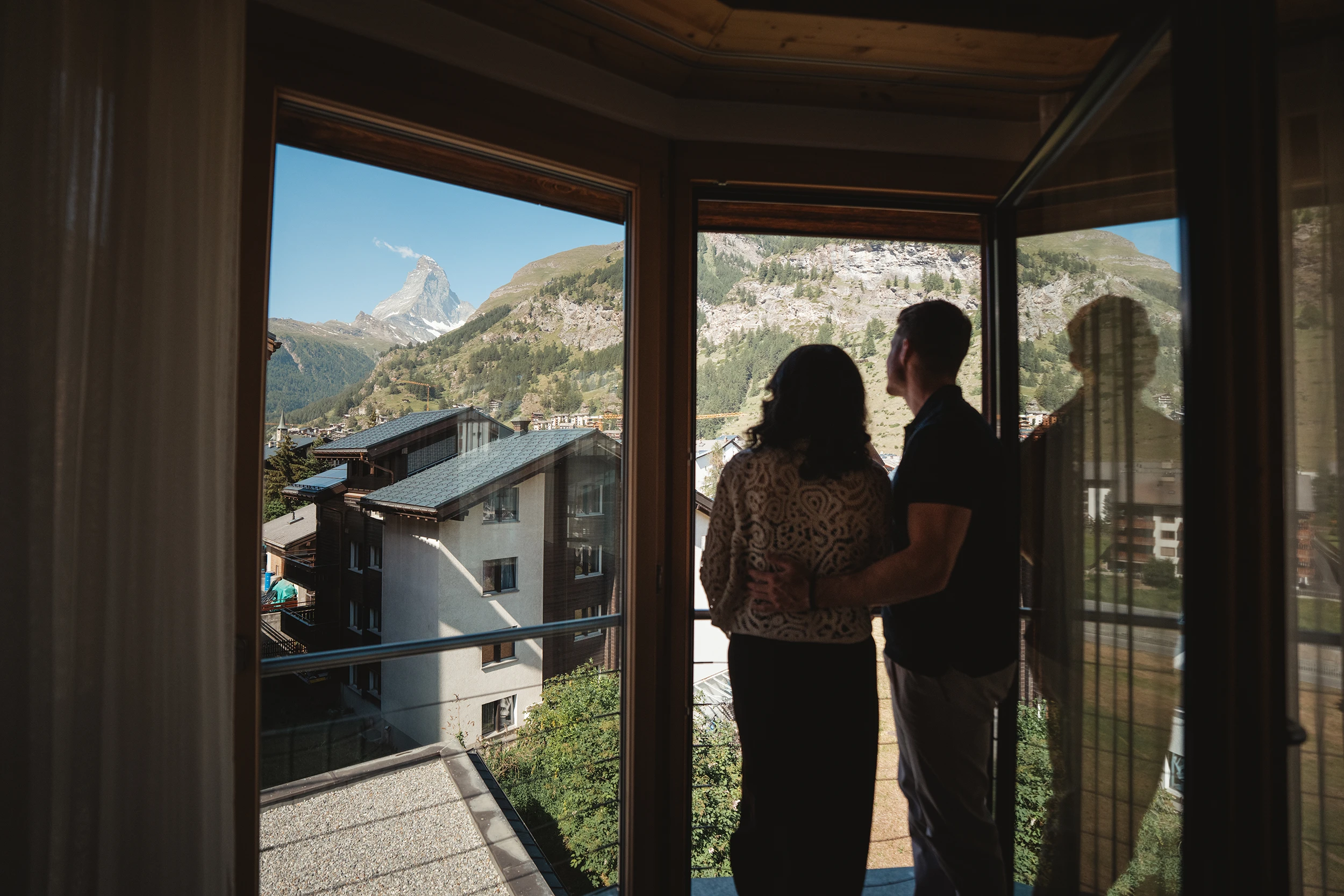 Paar am Zimmerfenster mit Blick auf Zermatt und das Matterhorn