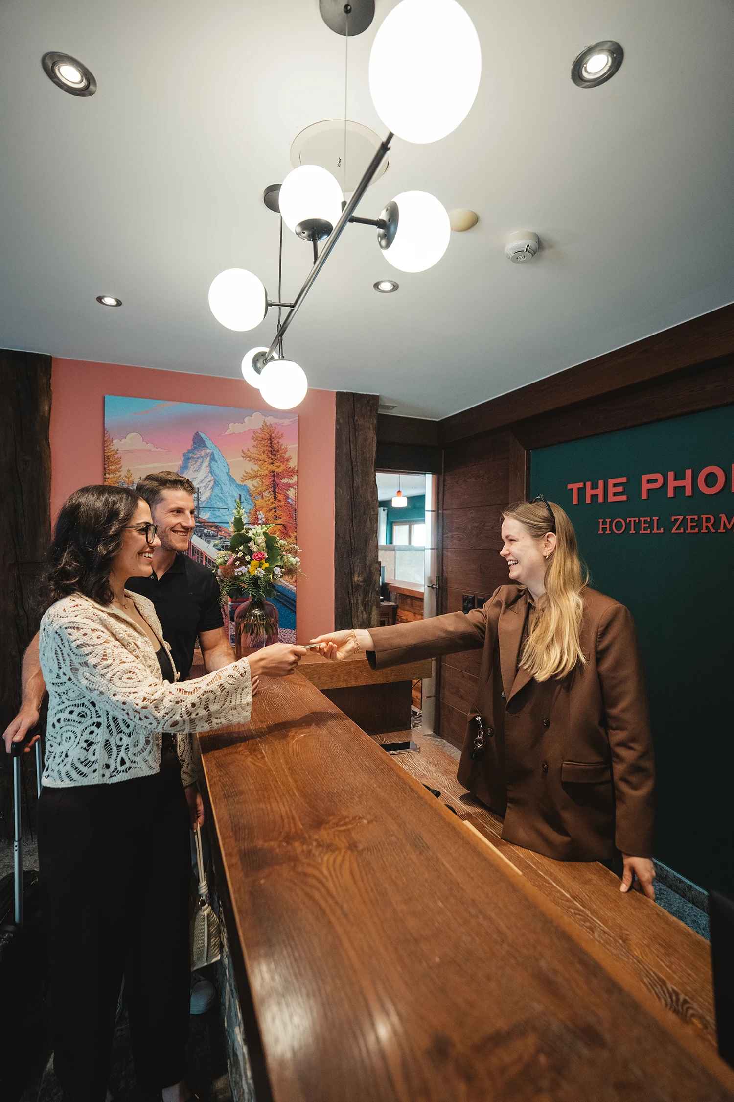 An employee greets a couple at the front desk of the Hotel Phoenix