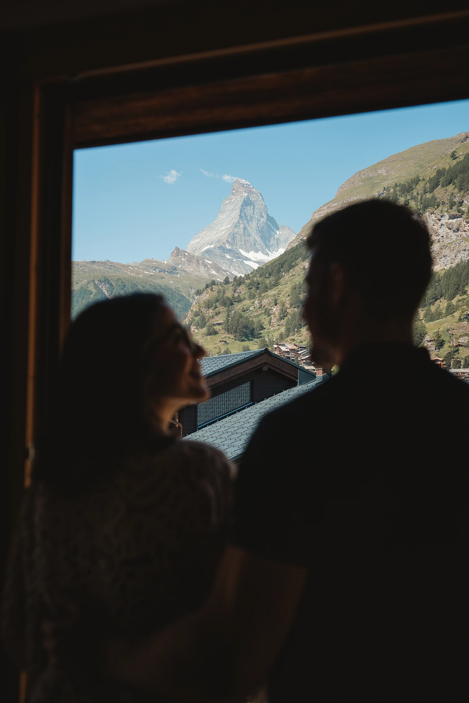 Paar blickt aus dem Zimmerfenster auf das Matterhorn