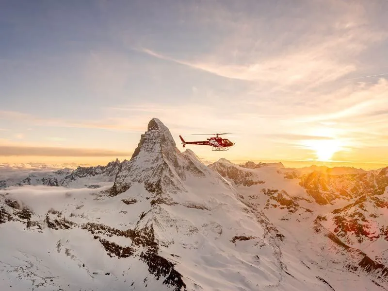 Roter Helikopter vor dem Matterhorn im Abendlicht