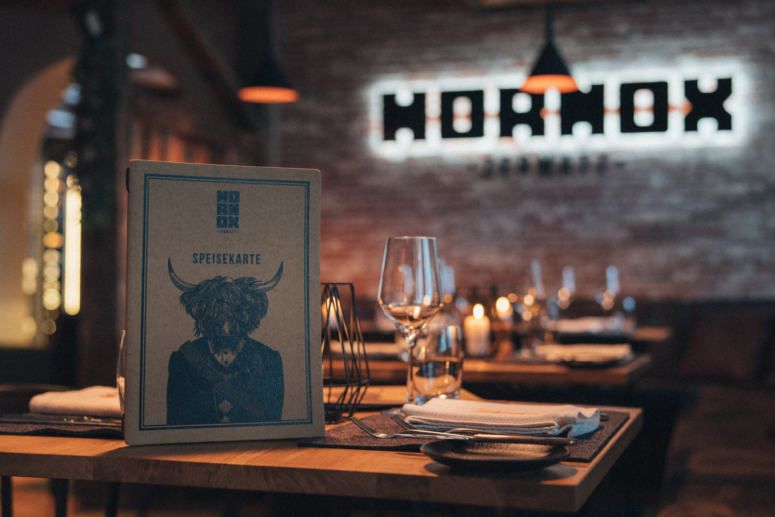 Speisekarte und gedeckter Tisch vor dem beleuchteten HORNOX-Schriftzug