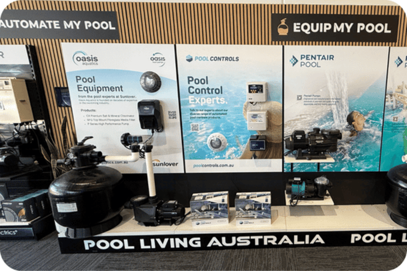 Display of pool equipment and control systems with banners for Oasis, Pool Controls, and Pentair Pool.