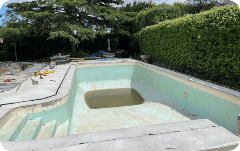 Empty outdoor pool with dirty water at the deep end and construction tools nearby.