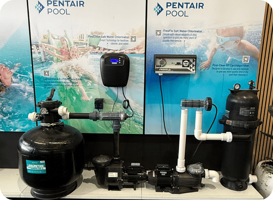 Pentair pool equipment display including filters, pumps, and chlorinator units in front of promotional panels.