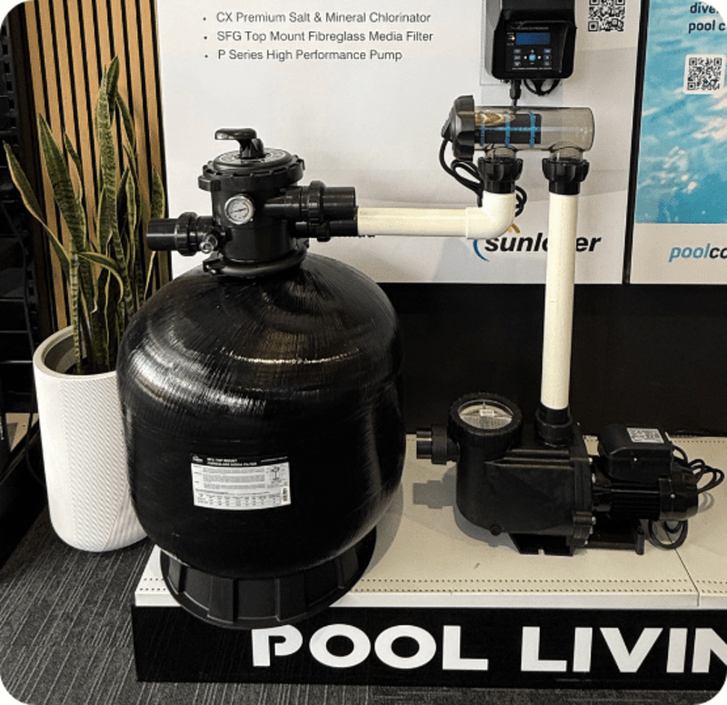 Black pool filter and pump system displayed on a stand with plant and signage in background.