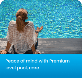 Woman sitting by a clear blue pool, meditating with her back to the camera.