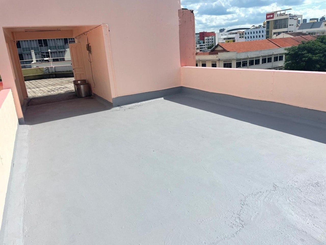Empty rooftop area with pink walls and city buildings in the background under a partly cloudy sky.