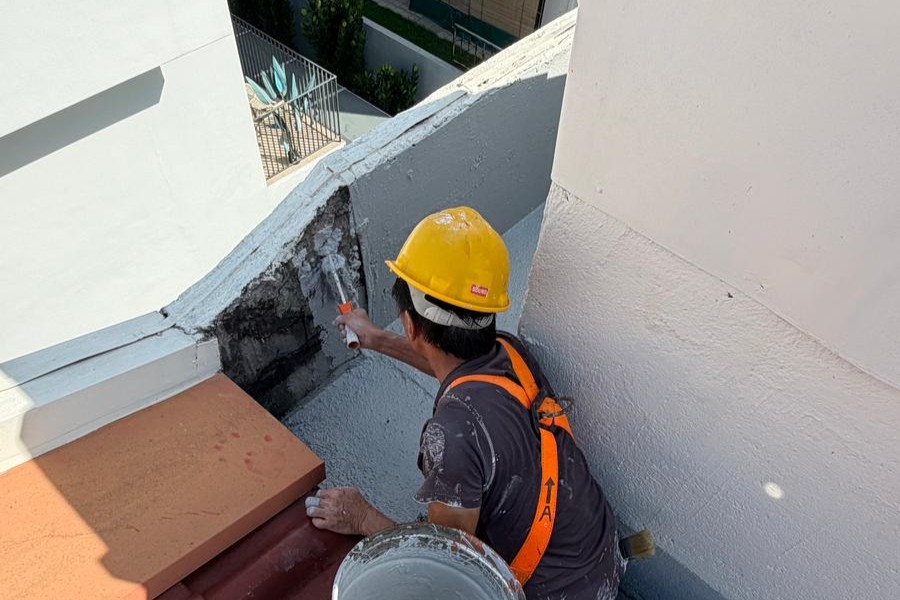 Worker in a yellow hard hat repairing a roof corner