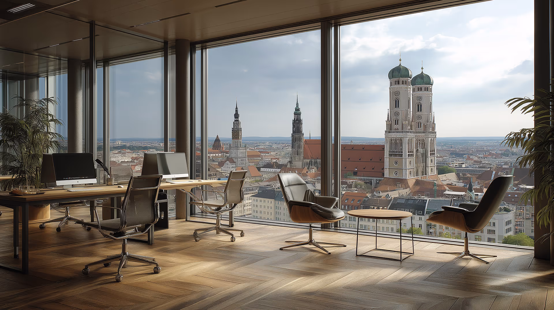 Modernes Büro mit Computern und Sesseln vor großen Fenstern mit Blick auf die Türme der Frauenkirche in München.