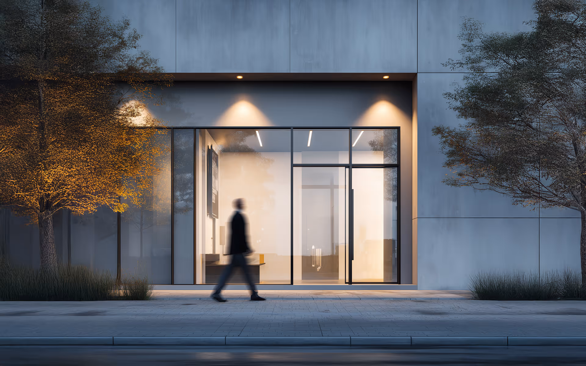Verwischte Menschenfigur geht auf Gehweg vor einem modernen Gebäude mit großen Glasfenstern und Beleuchtung.