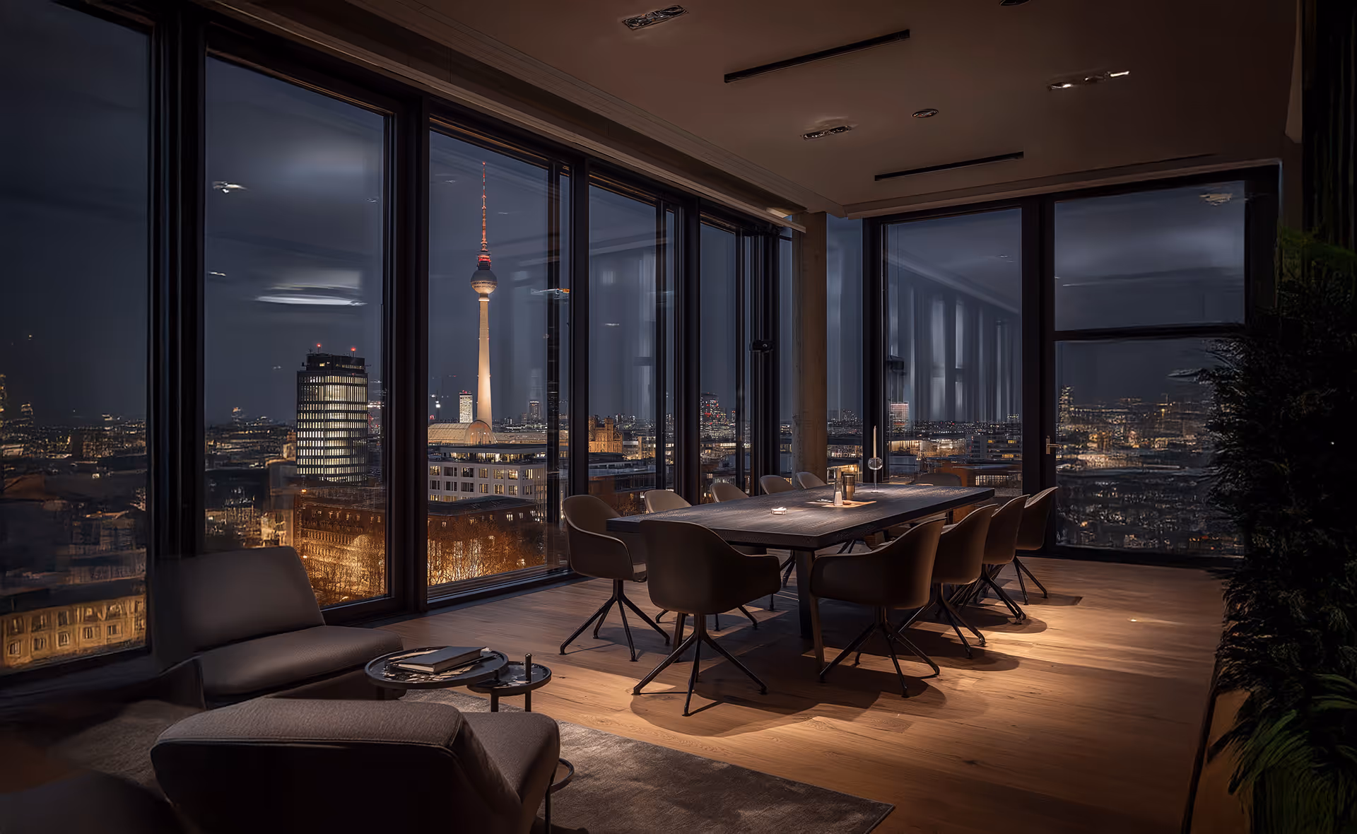 Modern Besprechungsraum mit großem Tisch und Stühlen vor bodentiefen Fenstern mit Blick auf den beleuchteten Berliner Fernsehturm bei Nacht.