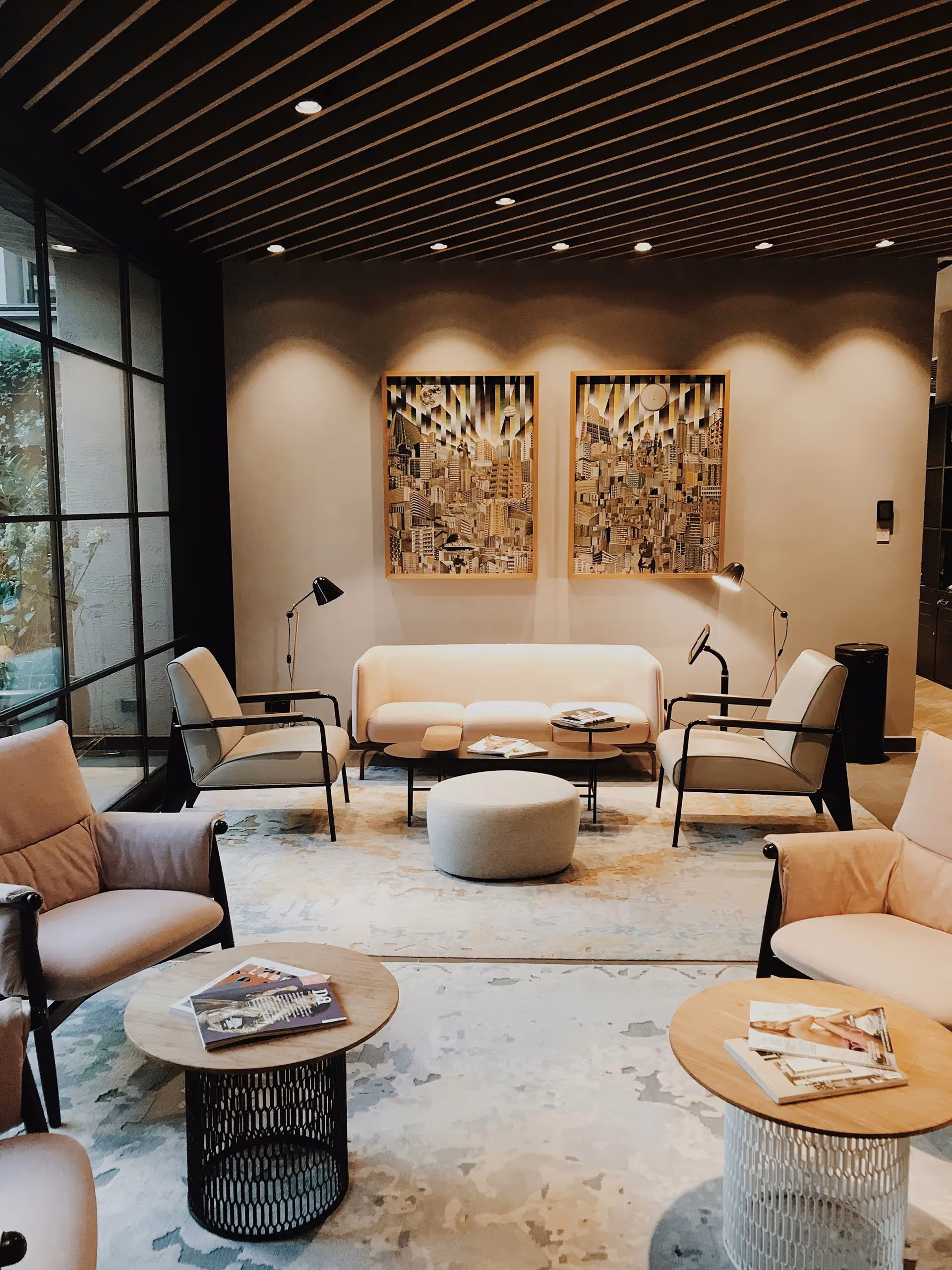 Modernes Wohnzimmer mit beiger Couch, beigen Sesseln, runden Beistelltischen und abstrakter Kunst an der Wand.