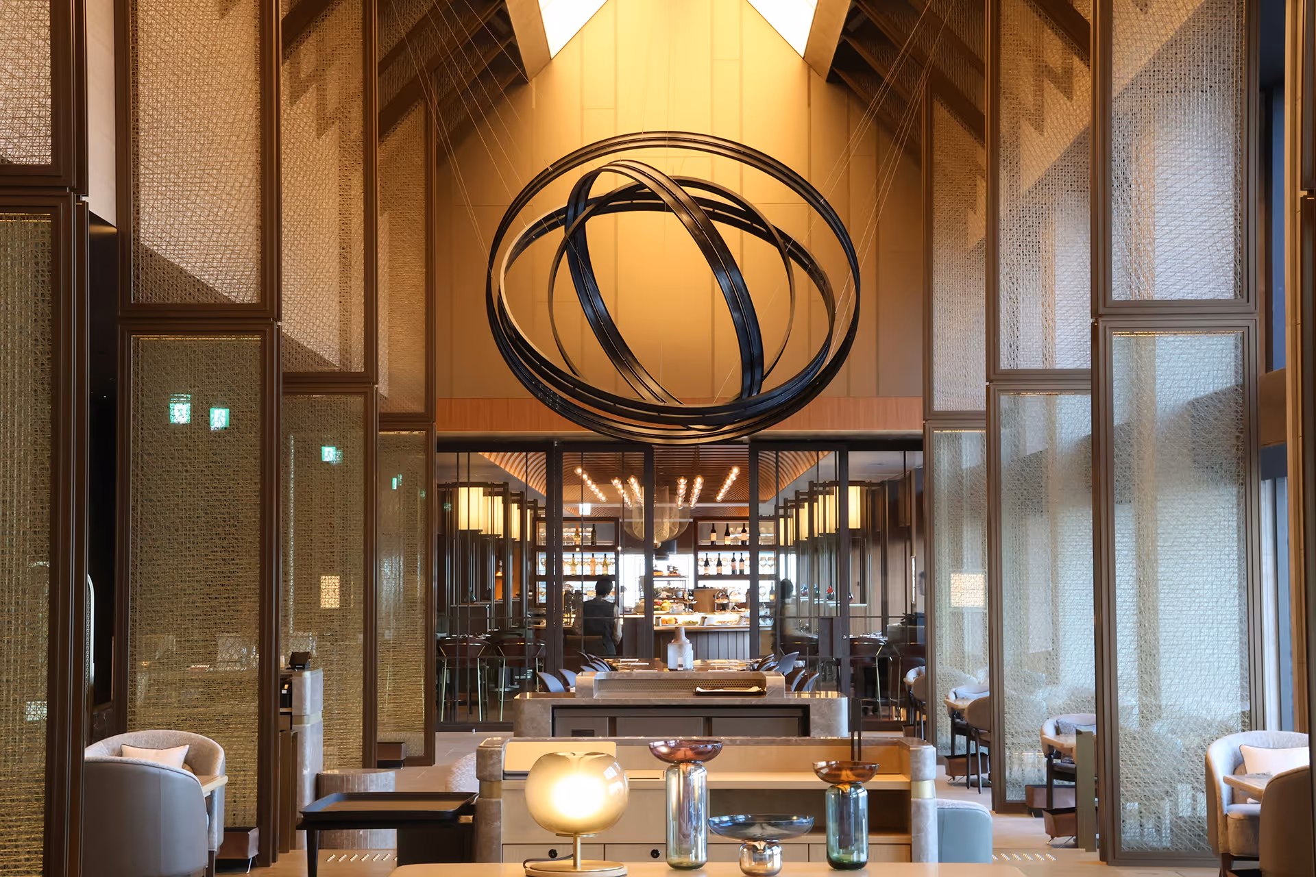 Elegantes Restaurantinterieur mit modernem metallischem Kronleuchter aus ineinandergreifenden Ringen und gemütlichen Sitzbereichen.