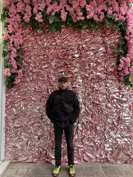 Andreas vor rosafarbener Installationswand mit Blumen
