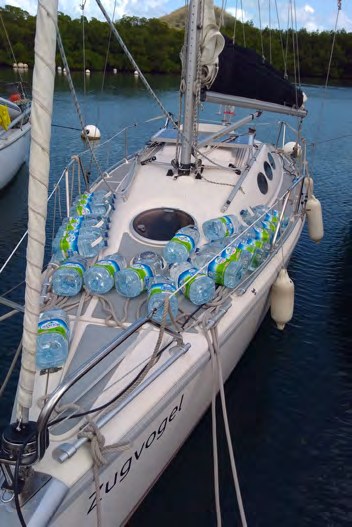 Segelboot, an dessen Reling zahlreiche Wasserflaschen hängen