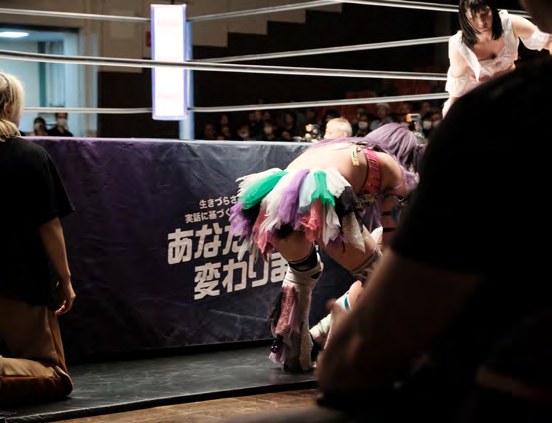 Wrestlerin an den Ringseilen, im Hintergrund das Publikum
