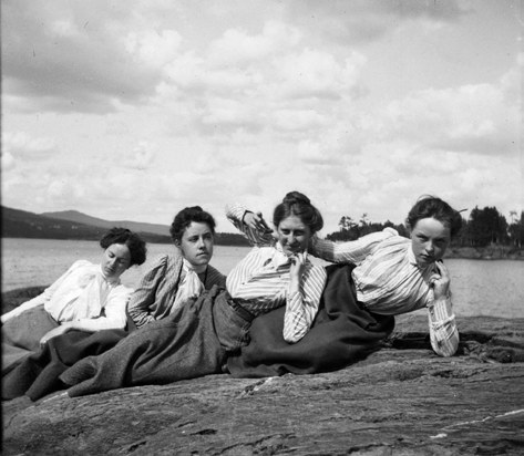 Historische Schwarzweißaufnahme: vier Frauen liegen am Ufer