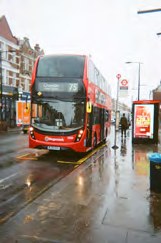 Roter Doppeldeckerbus auf einer regennassen Straße in London
