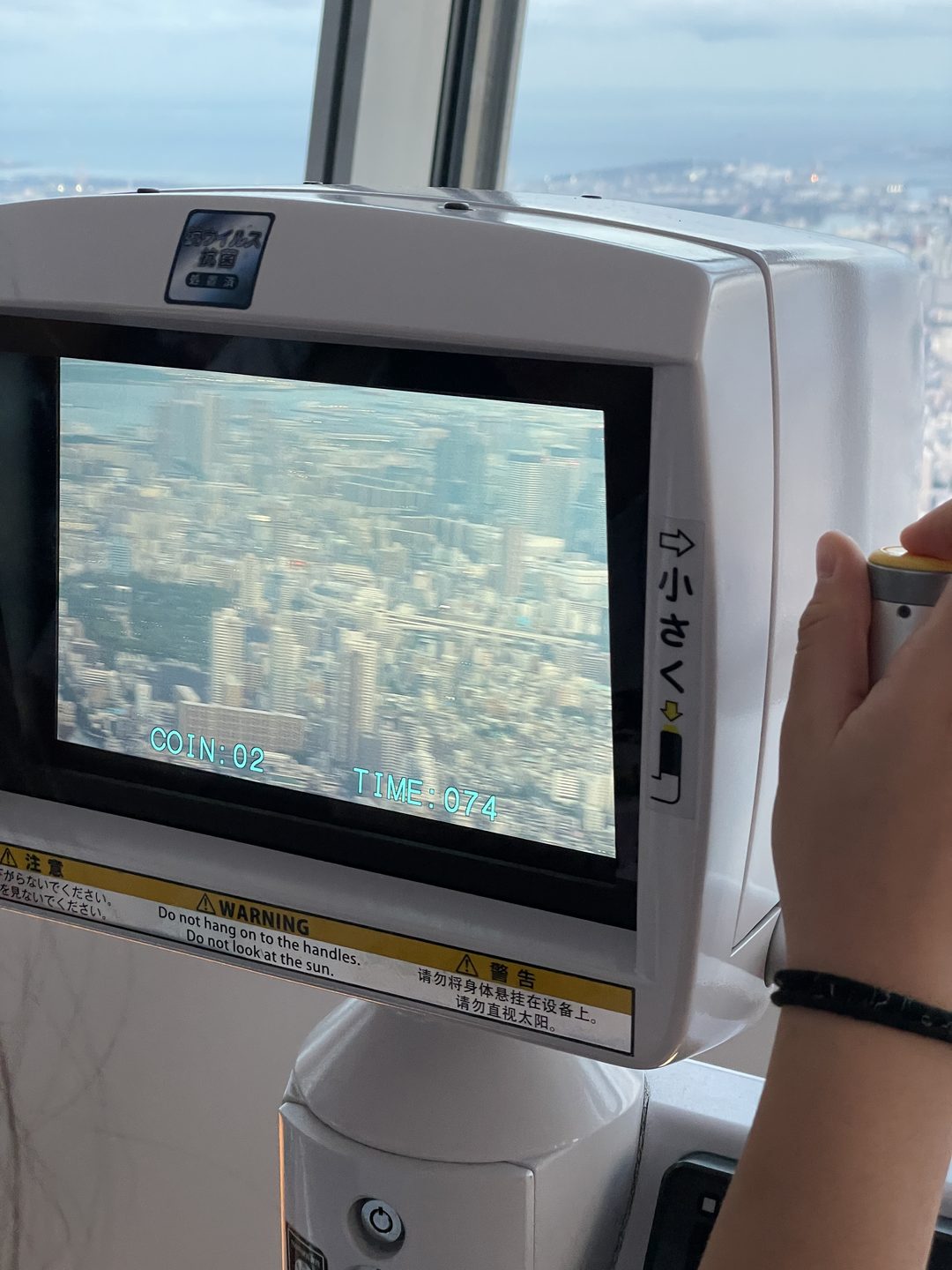 Bildschirm eines Münzfernrohrs hoch über Tokio, darauf ein unscharfes Häusermeer