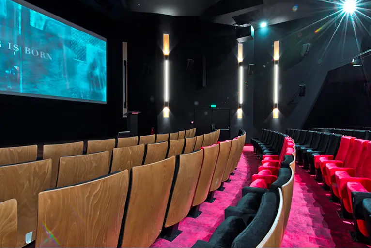 Salle de cinéma de l'Élysées Biarritz avec fauteuils en bois et velours rouge