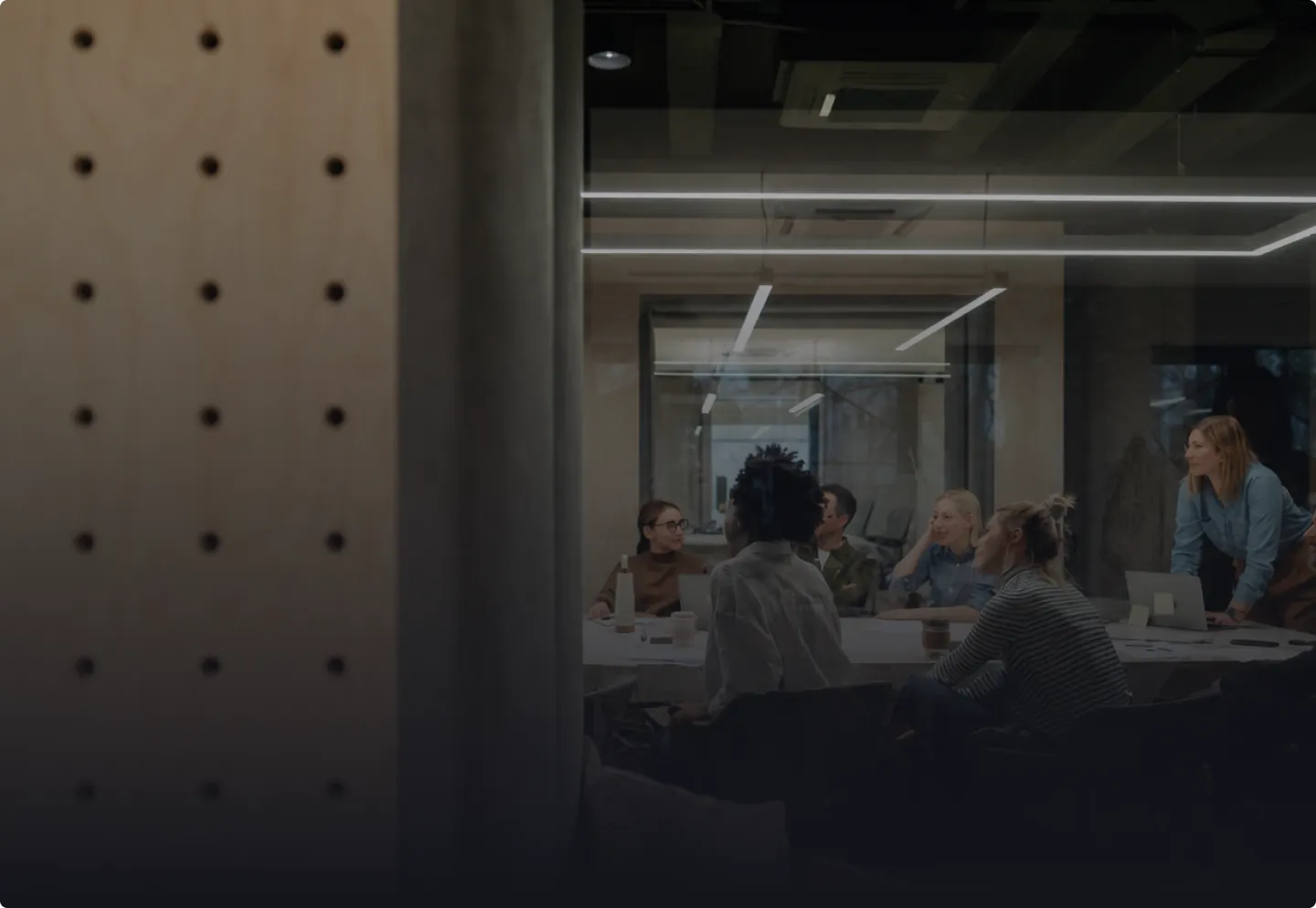 A group of six diverse people in a modern office having a meeting around a table.