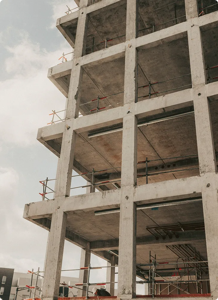 Unvollendetes Betongebäude mit Gerüsten und Absperrungen auf einer Baustelle.