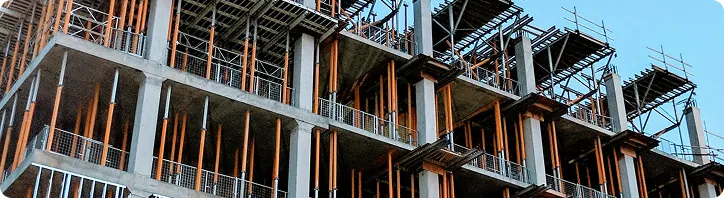 Rohbau eines mehrstöckigen Gebäudes mit Beton und Stahlgerüsten unter klarem Himmel.
