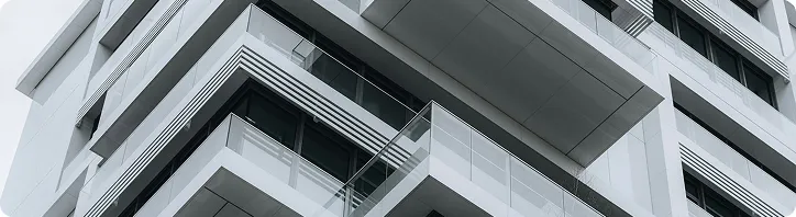 Moderne weiße Wohngebäude mit Balkonen und Glasgeländern in einem minimalistischen Stil.