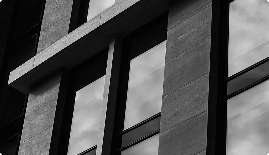 Fassade eines Gebäudes mit großen Fenstern und Betonstreben in Schwarz-Weiß.