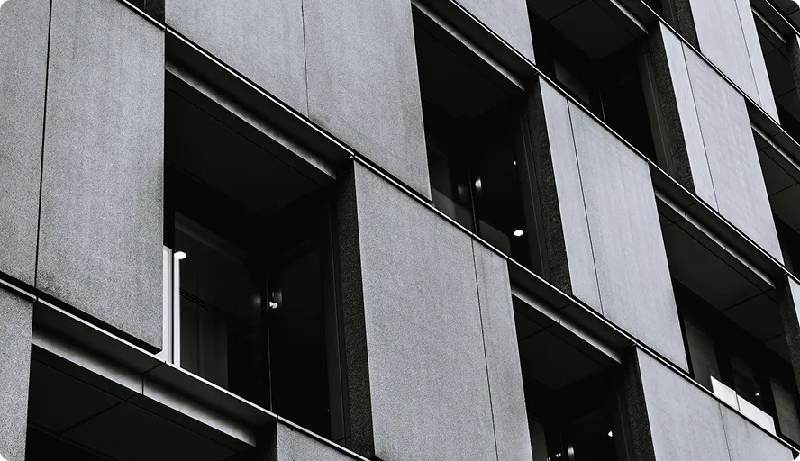 Fassade eines modernen Bürogebäudes mit großen, quadratischen Fenstern und grauen Paneelen.