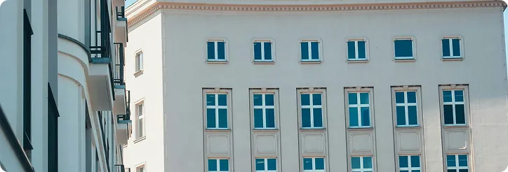 Fassade eines modernen Gebäudes mit mehreren Fenstern und weißen Wänden.