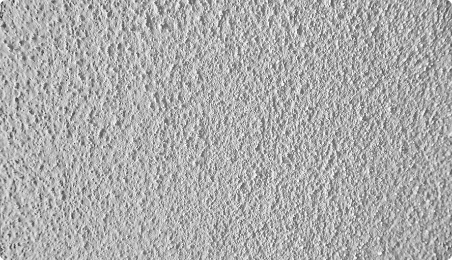Grau strukturierte Wand mit ungleichmäßiger Oberfläche und kleinen Unebenheiten.