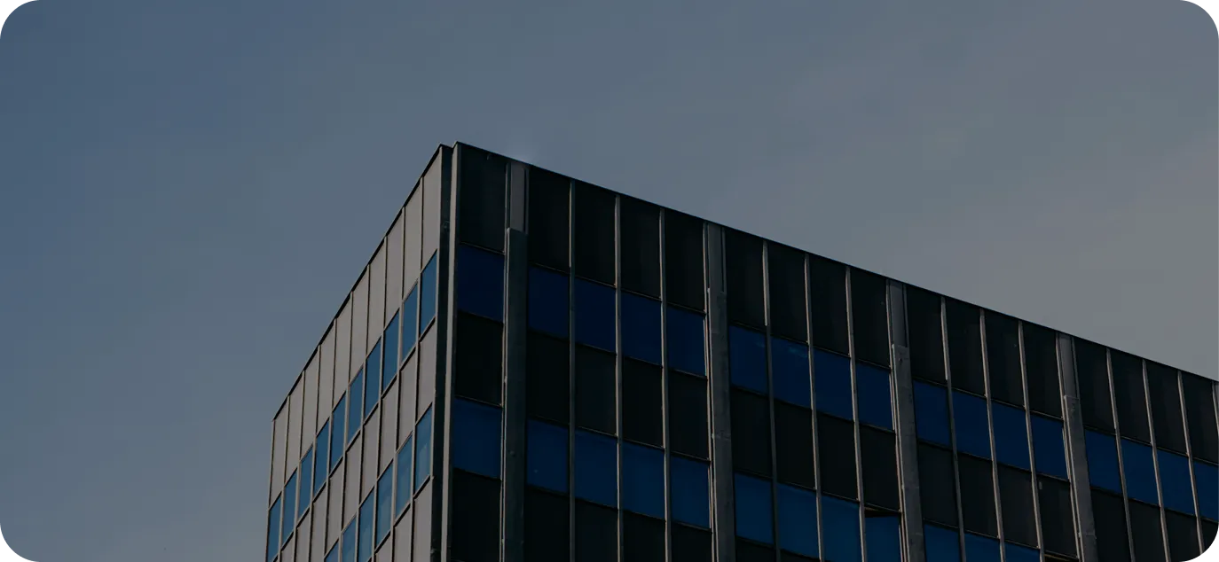 Moderne Wohnhäuser mit Balkonen, Grünflächen und Parkplätzen unter blauem Himmel.