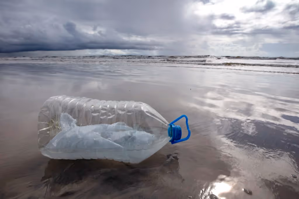 plastic jug with a plastic bag inside it on a beach