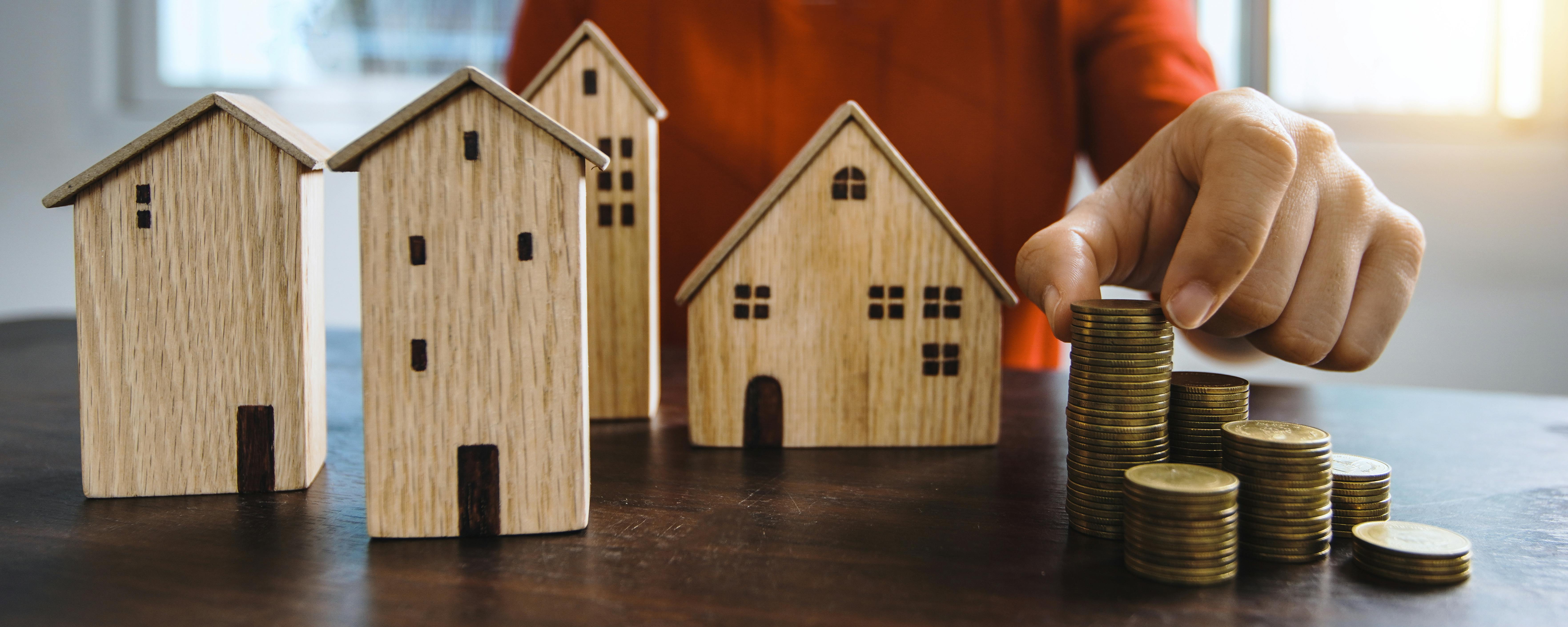 Maisons en bois miniatures alignées à côté de piles de pièces