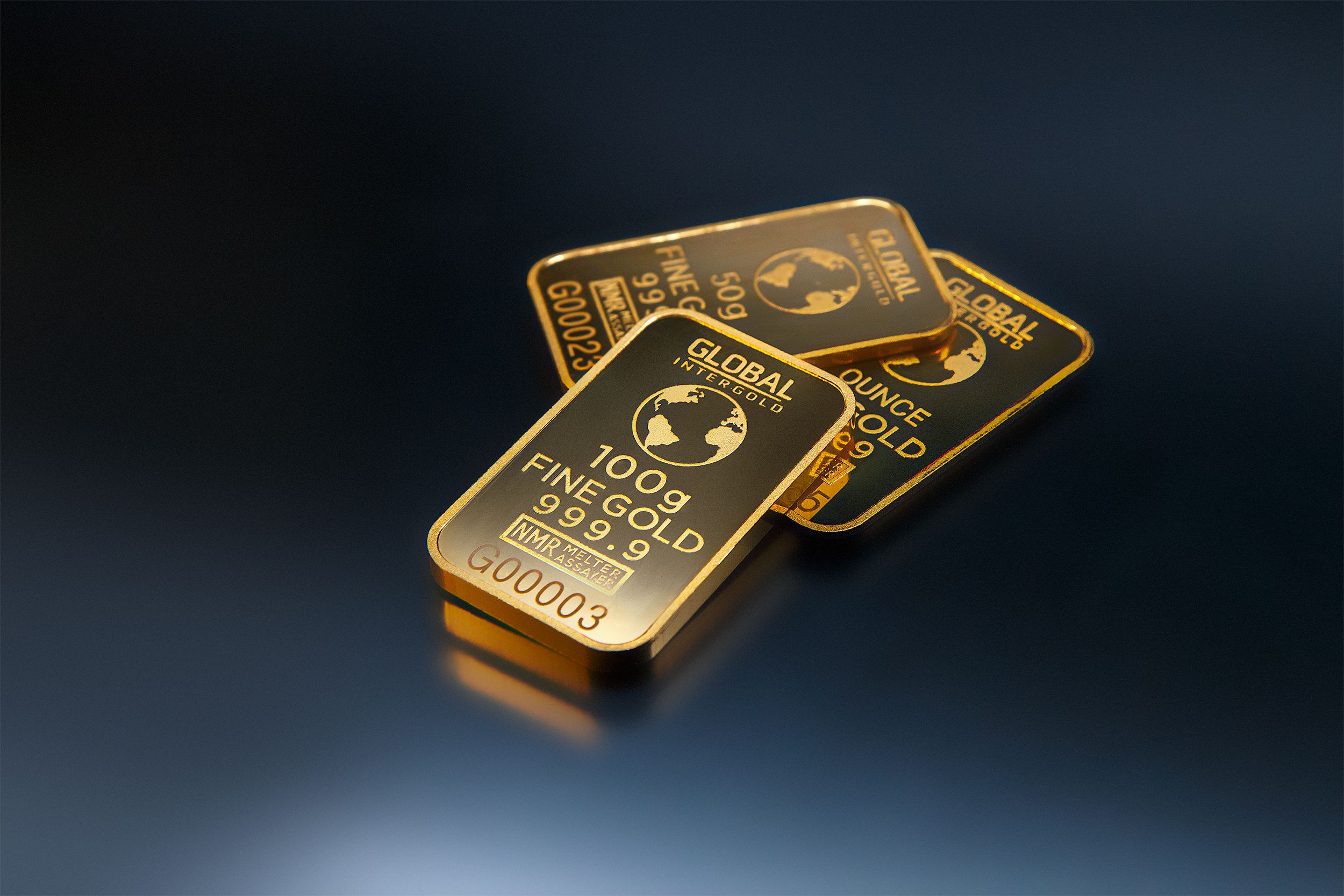 Trois lingots d'or posés sur un fond sombre