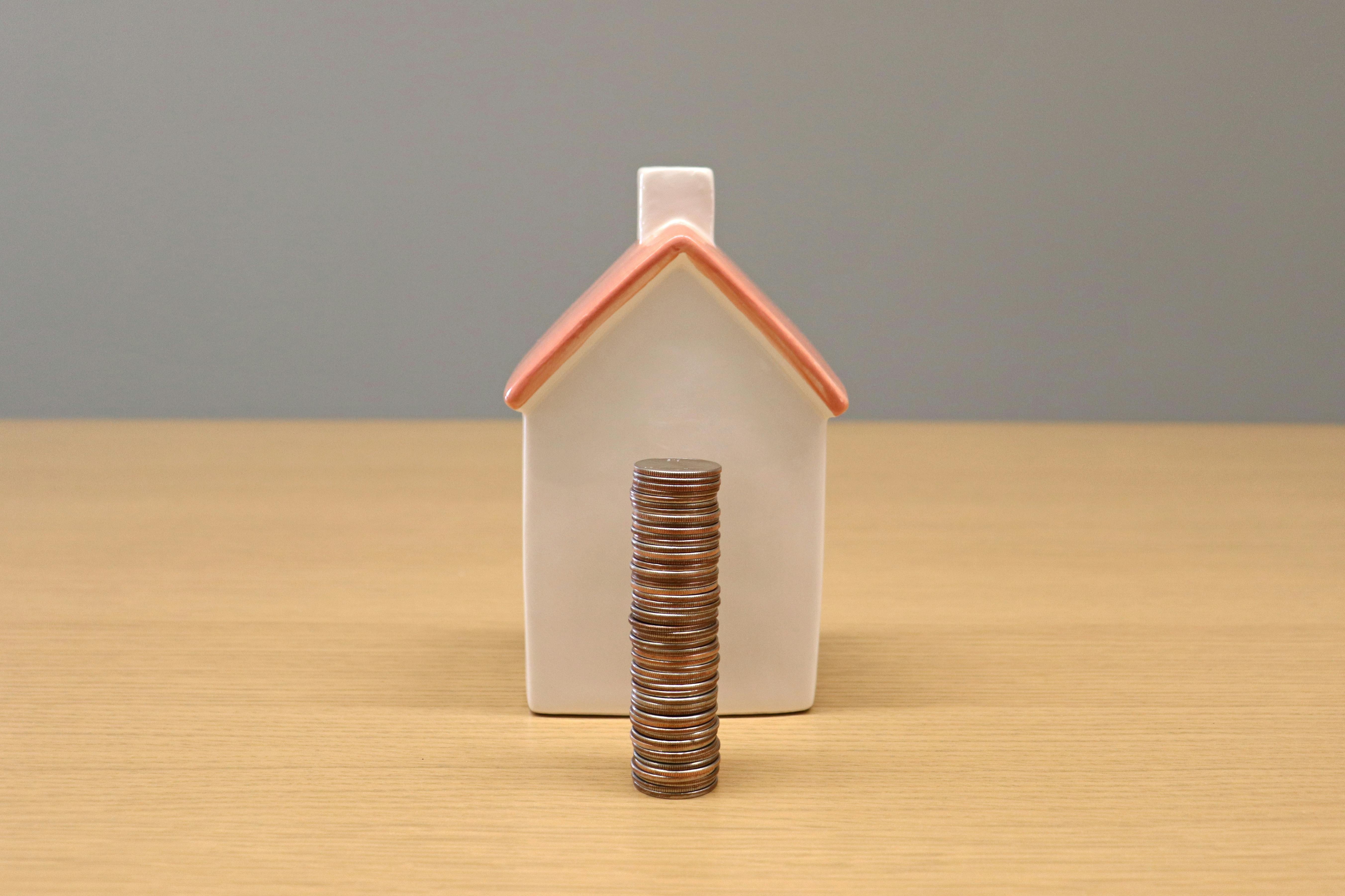 Maison miniature posée sur une pile de pièces